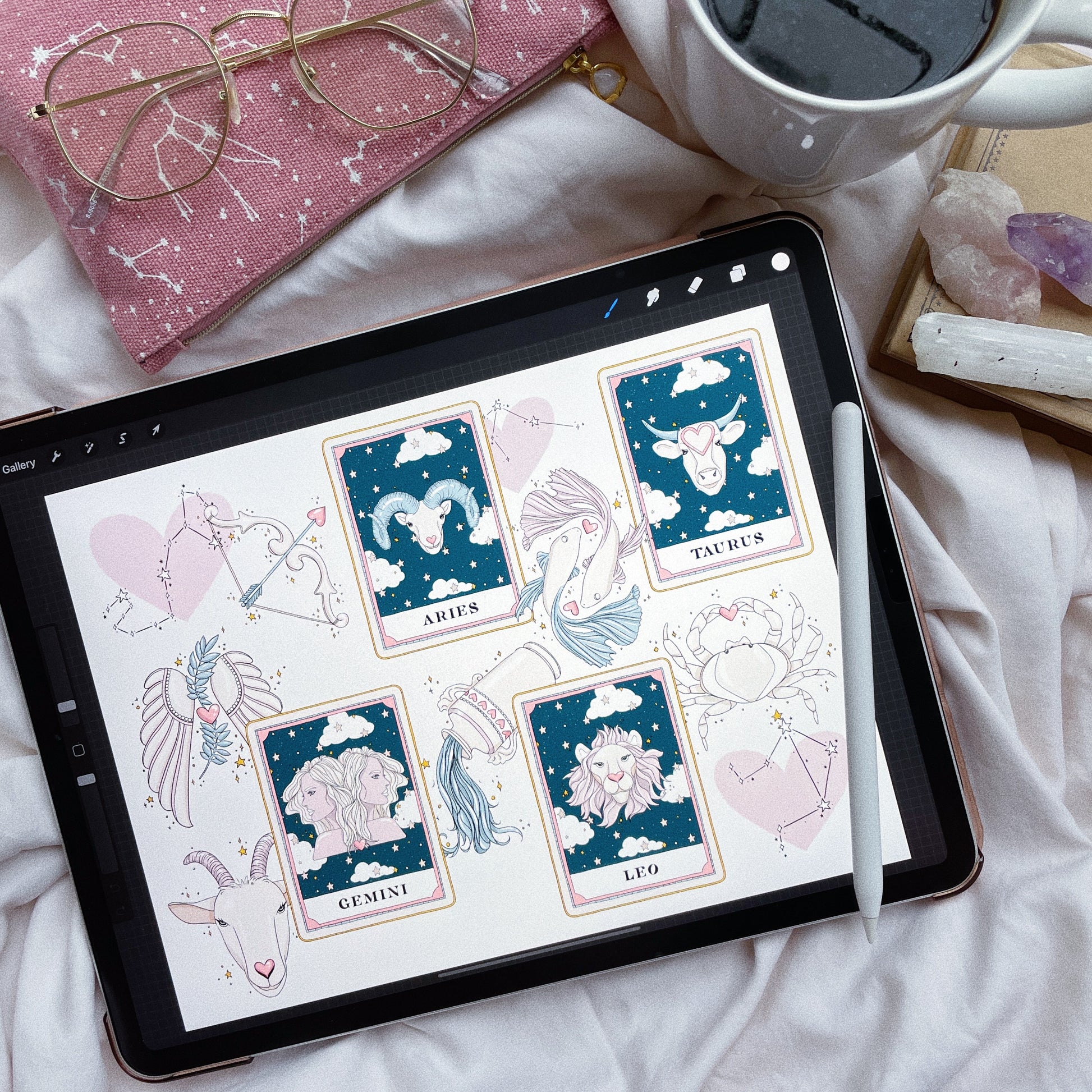 A collage of hand-drawn zodiac signs and celestial clipart including Aries, Leo, Scorpio, and Pisces symbols with mystical and starry backgrounds on an ipad next to coffee and crystals.