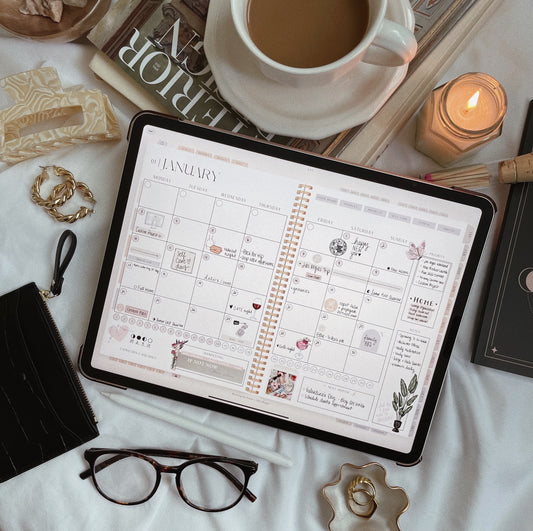 A tablet with the digital planner open beside coffee, glasses, and notebook on a cozy desk scene.