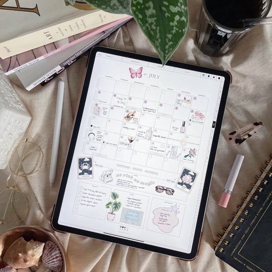 Digital planner open on a cozy surface with stylus and coffee, featuring vertical monthly layout.